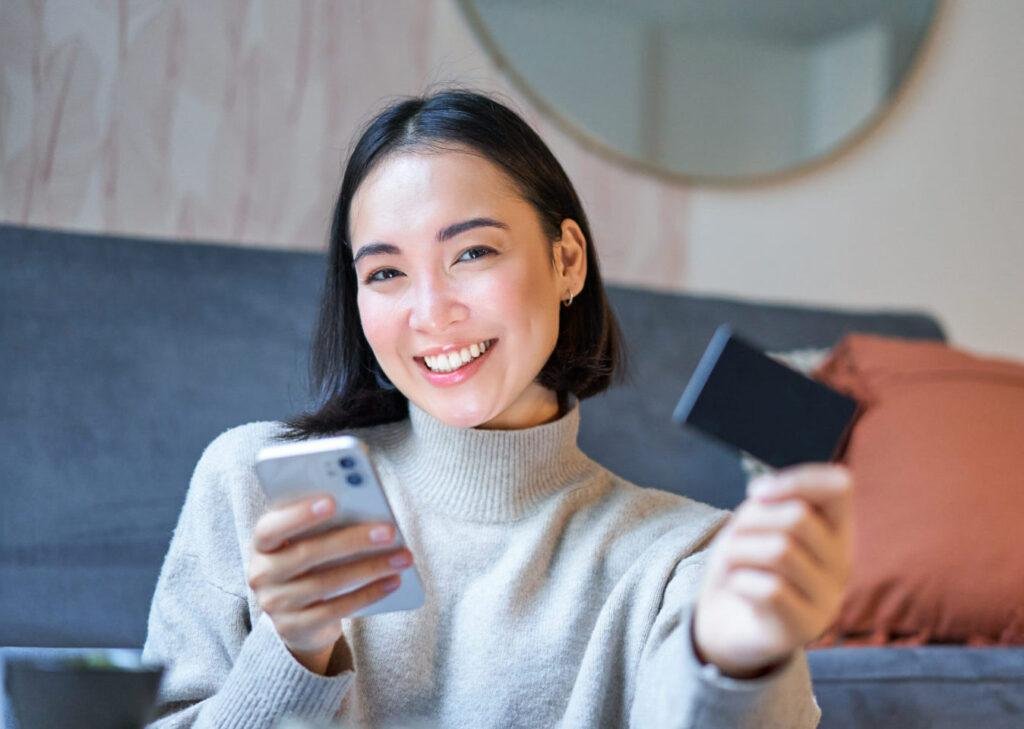 Smiling happy Asian lady using good tech in her hands - Image by Freepik
